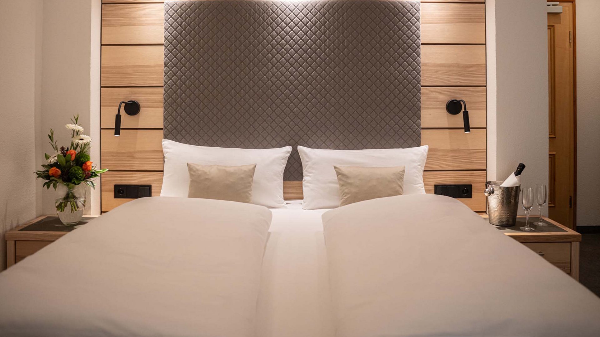Modern hotel room with double bed, reading lamps, and flower vase