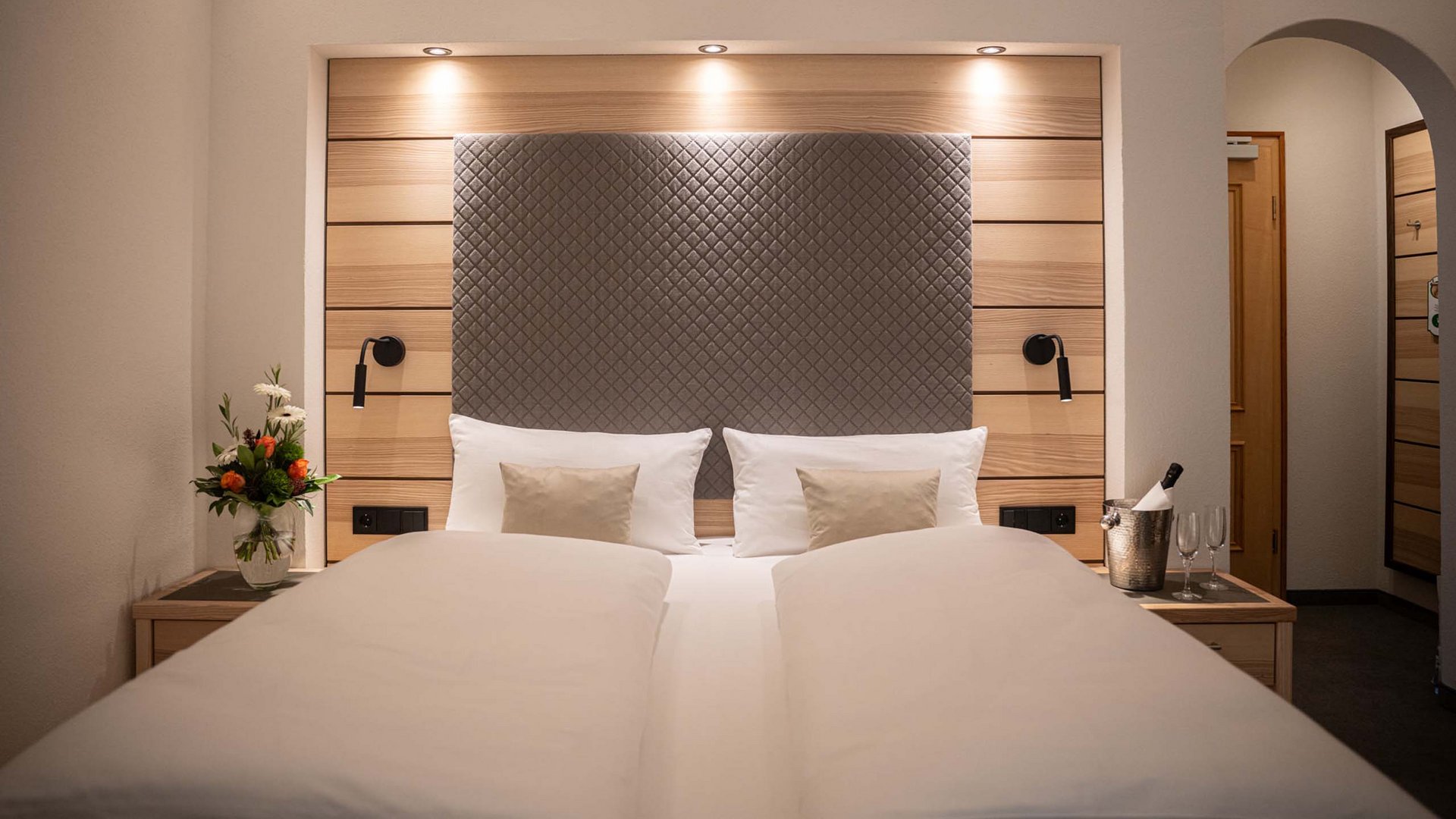 Modern hotel room with double bed, reading lamps, and flower vase