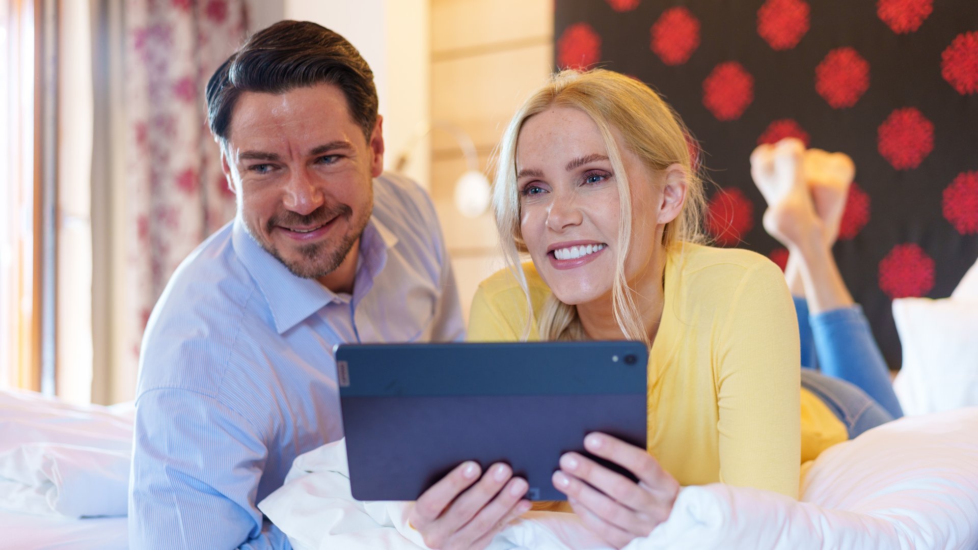 Couple lying on bed watching something on a tablet together