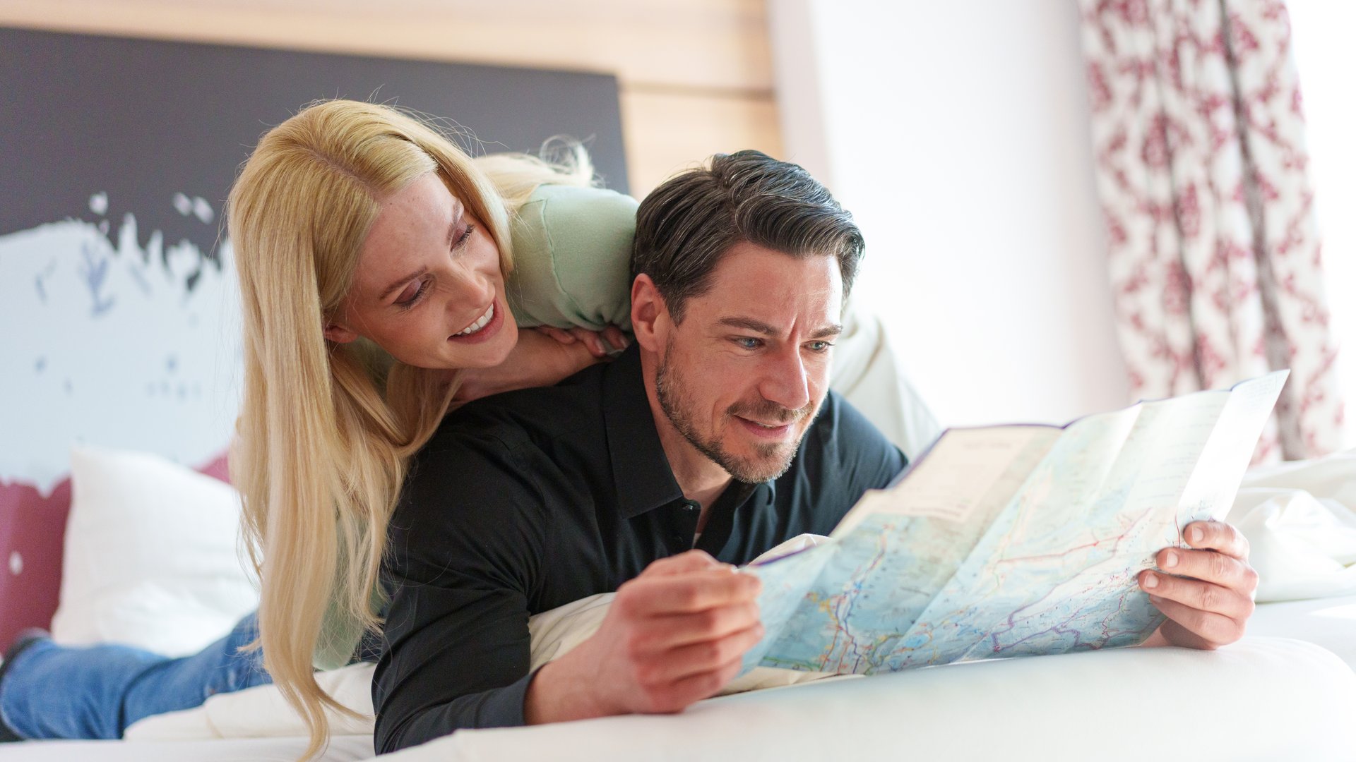 Couple planning trip on bed with a map