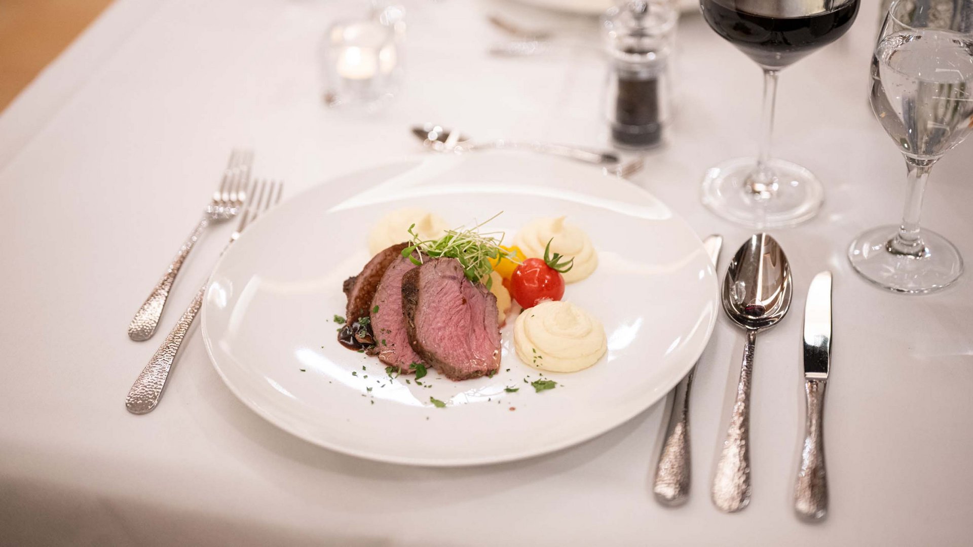Frühstück, kulinarisches Angebot & Lieblingsrestaurants Gedeckter Tisch mit Steak, Kartoffelpüree, Tomate und Rotwein